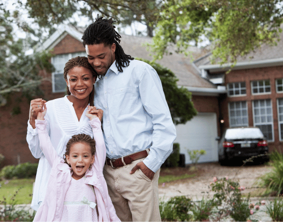 Happy family of 3 standing in front of their new home